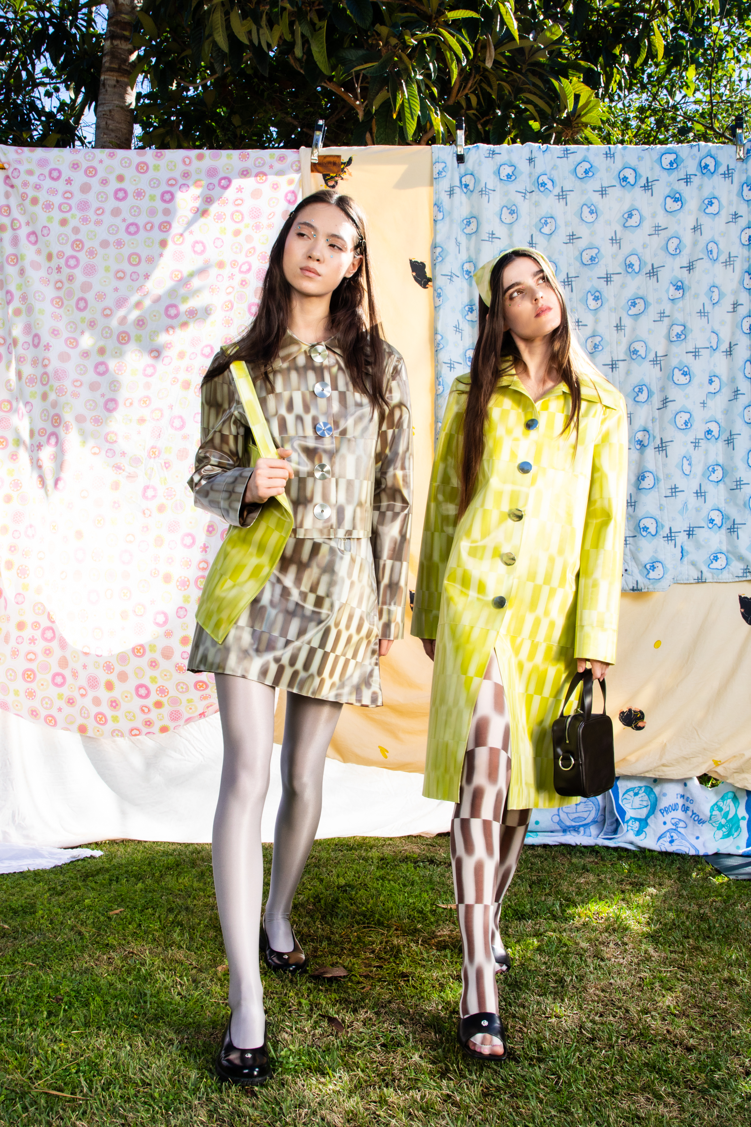 Two models in checker print lenticular matching outifts walking towards the camera against a backdrop of patterned quilts.